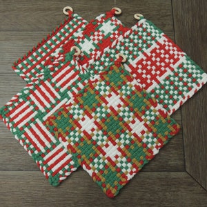 May include: Four woven pot holders in red, green, and white with a checkered pattern. The pot holders have wooden rings for hanging.