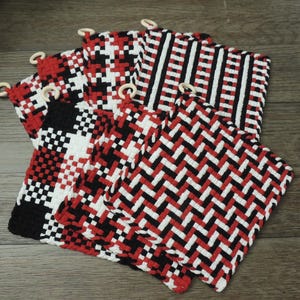 May include: A set of seven red, black, and white woven pot holders with wooden rings. The pot holders feature different geometric patterns.