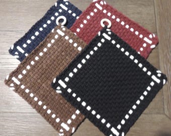 May include: Four square woven potholders in navy blue, brown, burgundy, and black. Each potholder has a white dotted border and a white loop for hanging. Kitchen and home decor.