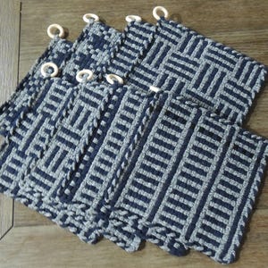May include: Set of six blue and white woven pot holders with a geometric pattern. Each pot holder has a loop for hanging.