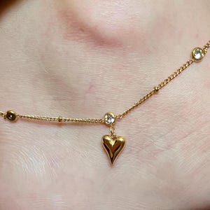 May include: A gold anklet with a heart charm and clear crystal accents.