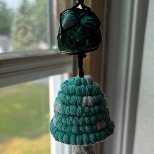 May include: A teal and white crocheted mushroom hanging ornament with a green and brown malachite stone at the top.