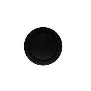 May include: A solid black, circular object with a raised, concentric rim. The object appears to be made of a matte material and is set against a plain white background. The design is simple and minimalist.