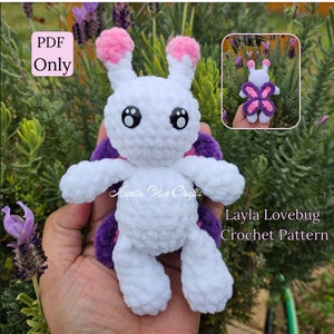 May include: A white crocheted lovebug with pink ears and purple wings. The lovebug is holding a purple flower. The text "Layla Lovebug Crochet Pattern" is written below the lovebug.