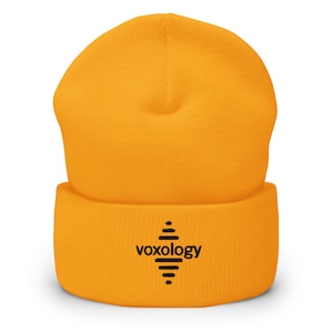 May include: A yellow beanie with a black embroidered logo that says "voxology" with a stylised honeycomb design.