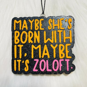 May include: Black glitter ornament with the text "Maybe she's born with it. Maybe it's Zoloft." in orange and pink lettering.