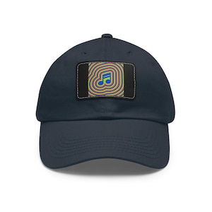 Op de afbeelding: Marineblauwe baseballcap met een rechthoekige patch met een muzieknootontwerp. De patch heeft een blauwe muzieknoot in het midden, omringd door concentrische cirkels in verschillende kleuren. De cap heeft een klassiek zes-panelen ontwerp.