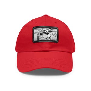 May include: A bright red baseball cap featuring a black and white patch with a vintage cartoon image of Mickey Mouse steering a ship's wheel. The cap is made of a soft fabric and has a curved brim.