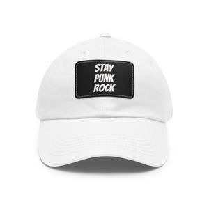 May include: White baseball cap with a curved peak. A black rectangular patch on the front features the words "STAY PUNK ROCK" in white, bold letters. The cap is made of a soft, durable fabric.