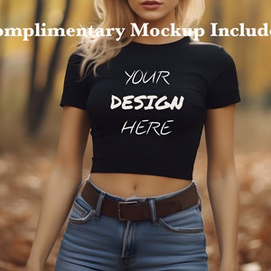以下が含まれることがあります： 白い文字で「YOUR DESIGN HERE」と書かれた、短い袖の黒いクロップトップ。森の中で人が着ています