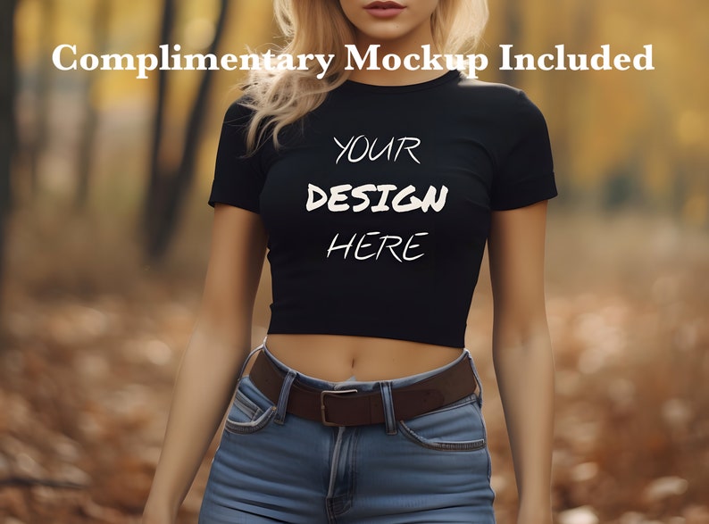 以下が含まれることがあります： 白い文字で「YOUR DESIGN HERE」と書かれた、短い袖の黒いクロップトップ。森の中で人が着ています
