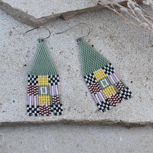 Op de afbeelding: Een paar groene, gele, roze, rode en zwarte kralen oorbellen met een geometrisch patroon.