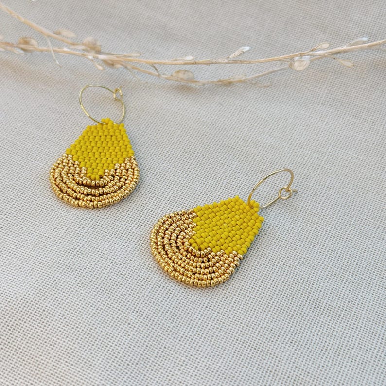 May include: A pair of yellow and gold beaded teardrop earrings with hoop closures.