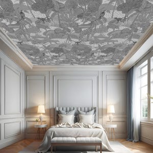 Puede incluir: Un dormitorio con un techo blanco con un papel tapiz estampado en blanco y negro. El papel tapiz tiene un tema de jungla con hojas, ramas y animales. La habitación tiene una cama grande con sábanas blancas y una cabecera gris. Hay dos lámparas en mesitas de noche a ambos lados de la cama. La habitación tiene una ventana grande con cortinas blancas y una alfombra gris en el suelo.