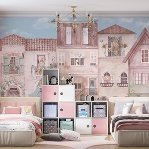 A wall mural featuring the musical animal village installed in a spacious twin bedroom with pink and grey bedding. The design is centered behind a white modular toy organizer, showing its versatility for large wall surfaces. The soft pastel colors create a calm yet playful environment for a children's sleeping area.