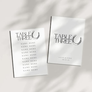 May include: Two white table cards with black text and a horseshoe graphic. The cards read "TABLE THREE" with a list of "NAME HERE" placeholders. One card includes the names "LILLIE & JAMES" and the date "08.01.25".