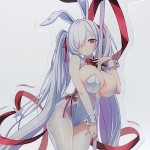 May include: An acrylic standee featuring an anime-style character with long white hair, bunny ears, and a white bodysuit, holding a pole topped with a large red bow. A small, chibi-style figure in a black hat and coat stands at the base of the pole.
