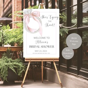 May include: A printable bridal shower welcome sign with a watercolor illustration of a ring with a pink bow. The sign says "She's Tying the Knot!" and "Welcome to Alicia's Bridal Shower" with the date "May 24, 2024".