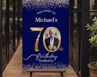 Könnte beinhalten: Ein blaues und goldenes Willkommens-Schild mit goldenem Glitzer für eine 70. Geburtstagsfeier. Das Schild lautet "Willkommen bei Michaels 70. Geburtstagsfeier". Ein Foto eines Mannes befindet sich in der Mitte des Schildes.