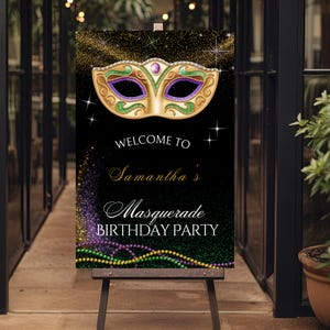 Op de afbeelding: Een zwart bord met gouden glitter en een goud, groen en paars maskerademasker. Op het bord staat "Welcome to Samantha's Masquerade Birthday Party" in elegant schrift. Groene, gouden en paarse kralen staan onderaan.