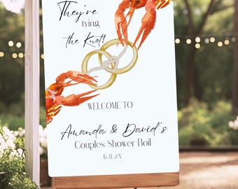 Puede incluir: Un cartel blanco con el texto "They're tying the knot!" y una ilustración de acuarela de dos cangrejos rojos sosteniendo anillos dorados con una cuerda blanca. El cartel también dice "Welcome to Amanda & David's Couples Shower Boil 6.8.2X".