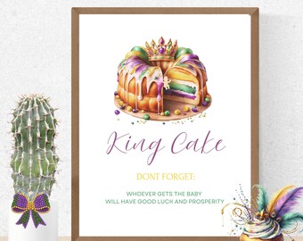 May include: A framed print featuring a watercolor illustration of a King Cake, with a slice cut out to reveal the colorful layers. The text "King Cake" is above the text "DON'T FORGET: WHOEVER GETS THE BABY WILL HAVE GOOD LUCK AND PROSPERITY."