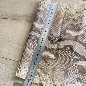 Genuine leather strips with natural python pattern laid on wooden background