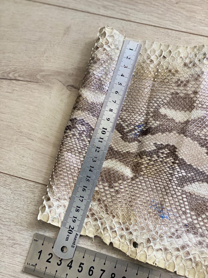 Genuine leather strips with natural python pattern laid on wooden background