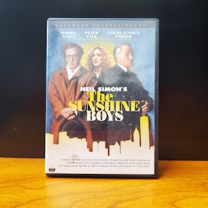 May include: DVD case for the movie "Neil Simon's The Sunshine Boys" starring Woody Allen, Peter Falk, and Sarah Jessica Parker. The case features a black background with a yellow and white title and a photo of the three actors.