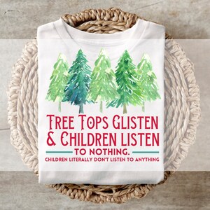 May include: White t-shirt featuring a watercolour design of five green Christmas trees. The text "TREE TOPS GLISTEN & CHILDREN LISTEN TO NOTHING. CHILDREN LITERALLY DON'T LISTEN TO ANYTHING" is printed in red and teal.