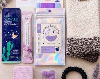 Może przedstawiać: Zestaw produktów do pielęgnacji, w tym maska do twarzy, plastry do spania, zatyczki do uszu, gumka do włosów i mydło o zapachu lawendy. Produkty ułożone są z gałązkami lawendy i kremową skarpetą. Opakowanie zawiera napisy takie jak "Dreamy Lavender" i "Breathing Techniques".