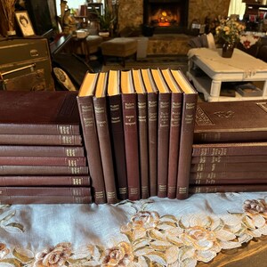 May include: A set of 20 brown hardcover books with gold lettering on the spines. The books are arranged in two rows, with the top row containing 14 books and the bottom row containing 6 books. The books are all the same size and shape, and they have a classic, elegant look.