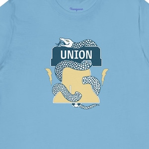 May include: A light blue t-shirt with a graphic of a snake wrapped around a bell with the word "UNION" on it.