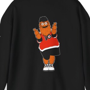 Op de afbeelding: Zwart hoodie met een grafische print van een cartoon mascotte die een hockeytrui draagt met de letter "P" erop.