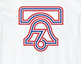 May include: White long-sleeve shirt featuring a red and blue graphic of a bell with the number 76 inside. The design is outlined in red and blue. The shirt has a crew neck and long sleeves.