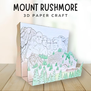 Puede incluir: Una manualidad de papel 3D que representa el Monte Rushmore, con los rostros de cuatro presidentes estadounidenses. La manualidad incluye una ilustración detallada de la montaña, árboles y un puente, con el texto "MOUNT RUSHMORE 3D PAPER CRAFT" en la parte superior.