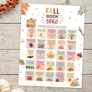 May include: A Fall Book Bingo game card featuring a grid of reading challenges with autumn-themed illustrations like pumpkins, leaves, and foxes. The text reads Fall Book Bingo and includes instructions to complete five challenges in a row.