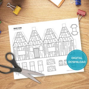 May include: A black and white paper craft template labeled "Bahay Kubo 3D Paper Craft" featuring a house design. Scissors and office supplies are on a wooden desk. A blue circle with the words "DIGITAL DOWNLOAD" is on the paper.