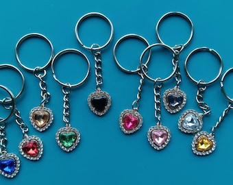 May include: Ten silver keychains with heart-shaped charms. Each charm features a different colored rhinestone in the center, surrounded by smaller rhinestones.