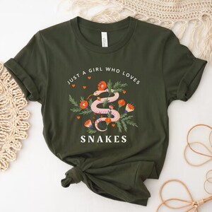 May include: A green t-shirt with the text "Just a girl who loves snakes" and a pink snake with orange flowers on it.