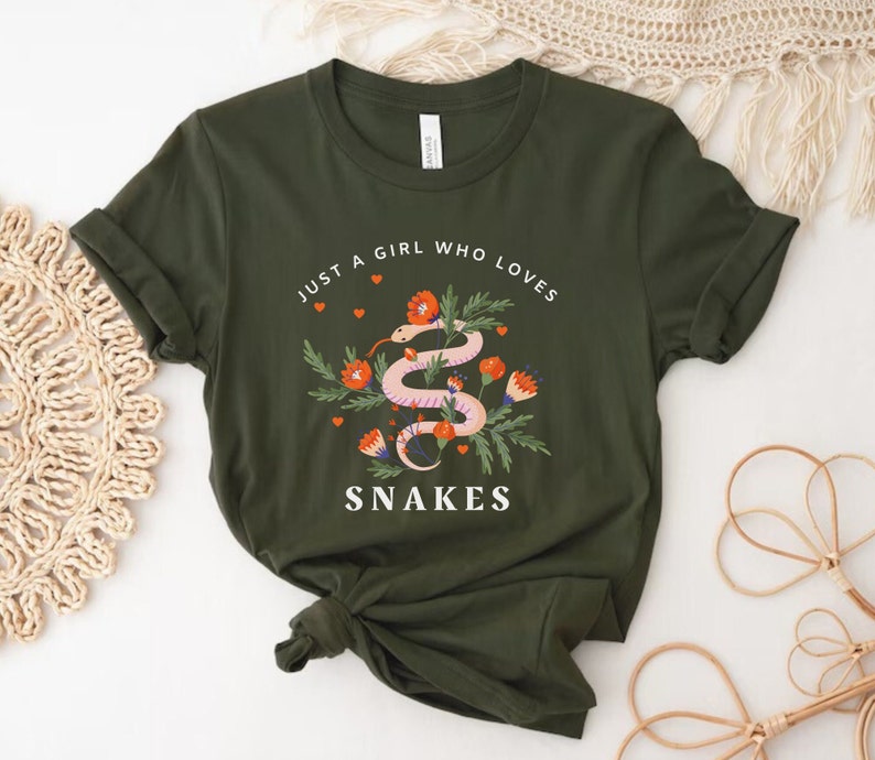 May include: A green t-shirt with the text "Just a girl who loves snakes" and a pink snake with orange flowers on it.