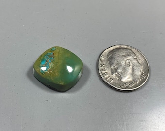 May include: A polished, square-shaped gemstone with a mix of green and turquoise hues. The stone is next to a U.S. dime for size comparison. The gemstone has a glossy finish and a unique pattern.