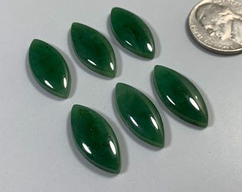 May include: Six polished, oval-shaped, dark green gemstones with a glossy finish. A US quarter coin is included for size comparison. The gemstones are arranged on a light gray surface.