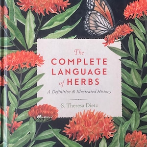 May include: A hardcover book titled The Complete Language of Herbs: A Definitive & Illustrated History by S. Theresa Dietz. The cover features a black background with vibrant orange flower clusters, green leaves, and a monarch butterfly illustration.