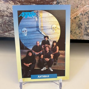 Puede incluir: Una tarjeta de intercambio azul y amarilla con una banda llamada Anthrax. La tarjeta tiene una imagen de los miembros de la banda frente a un reloj con calaveras.
