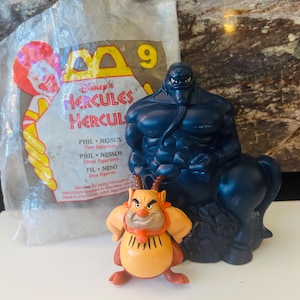 May include: A collection of Disney's Hercules figurines, including Phil, Nessus, and a dark blue centaur-like figure. The figures are displayed with a McDonald's packaging featuring the Hercules logo and the number 9.