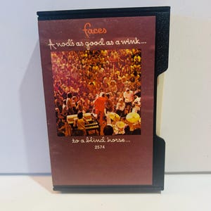 May include: A vintage cassette tape case with a maroon label featuring the band name "Faces" and the text "A nod's as good as a wink... to a blind horse..." with a concert image. The case is black.