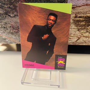 May include: A Keith Sweat ProSet Superstars Musicards trading card. The card features a portrait of Keith Sweat in a black suit. The card has a pink and green border with the Superstars logo.