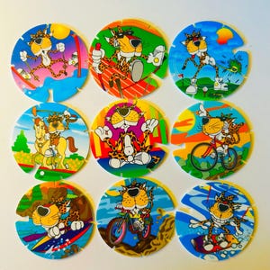 May include: Nine colorful, circular collectible game pieces featuring a cartoon cheetah character in various action poses. The cheetah is depicted skiing, golfing, riding a horse, meditating, riding a bike, surfing, and riding a mountain bike.