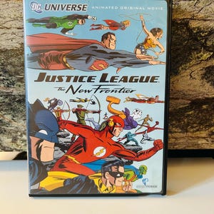 May include: DVD case for the animated movie "Justice League: The New Frontier." The cover features a comic book style illustration of Superman, Wonder Woman, The Flash, and other DC Comics superheroes in action. The title "DC Universe Animated Original Movie" is also visible.